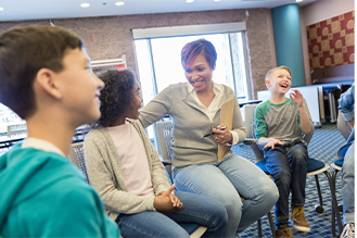 one adult sitting in a circle with three students